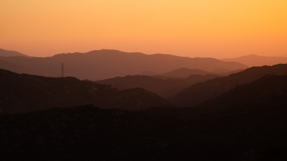 the sun is setting over a mountain range