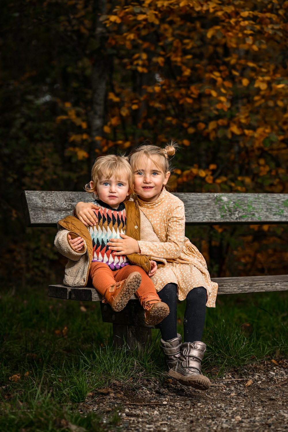 two little girls sitting on a wooden bench