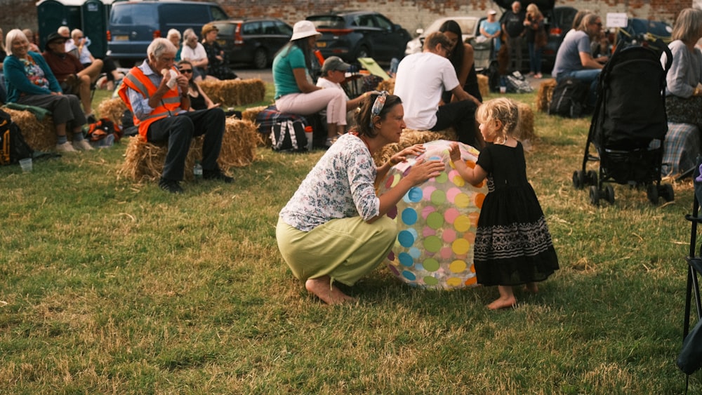 a woman kneeling down next to a little girl