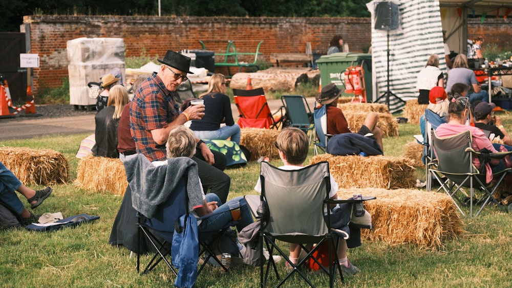 a group of people sitting on top of a lush green field