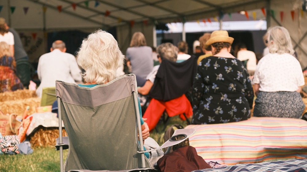 a group of people sitting in lawn chairs under a tent