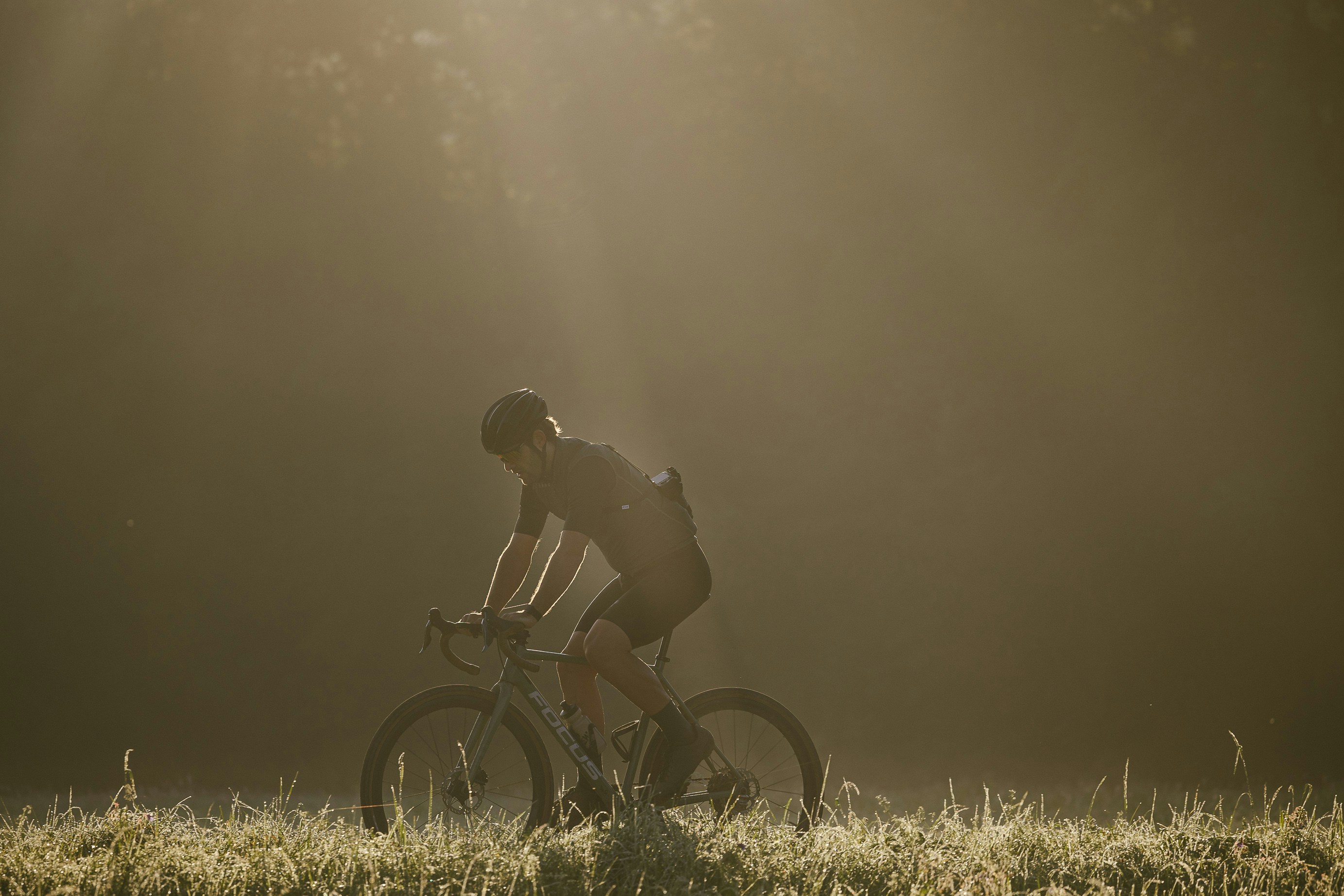 a man riding a bike through a lush green field