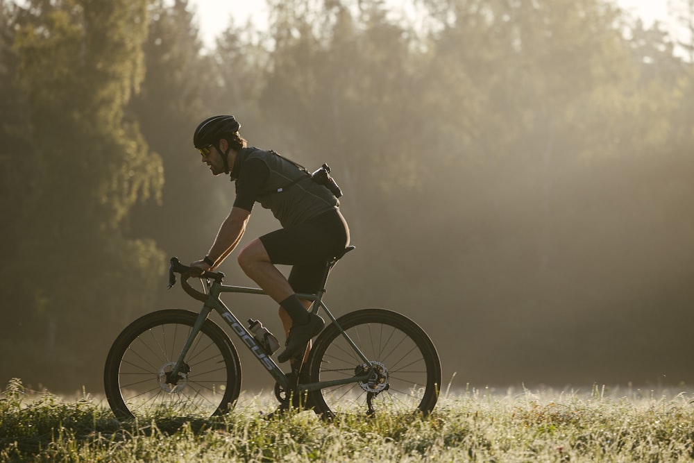 a man riding a bike through a lush green field