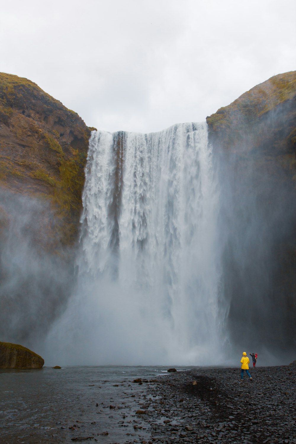 two people standing in front of a waterfall