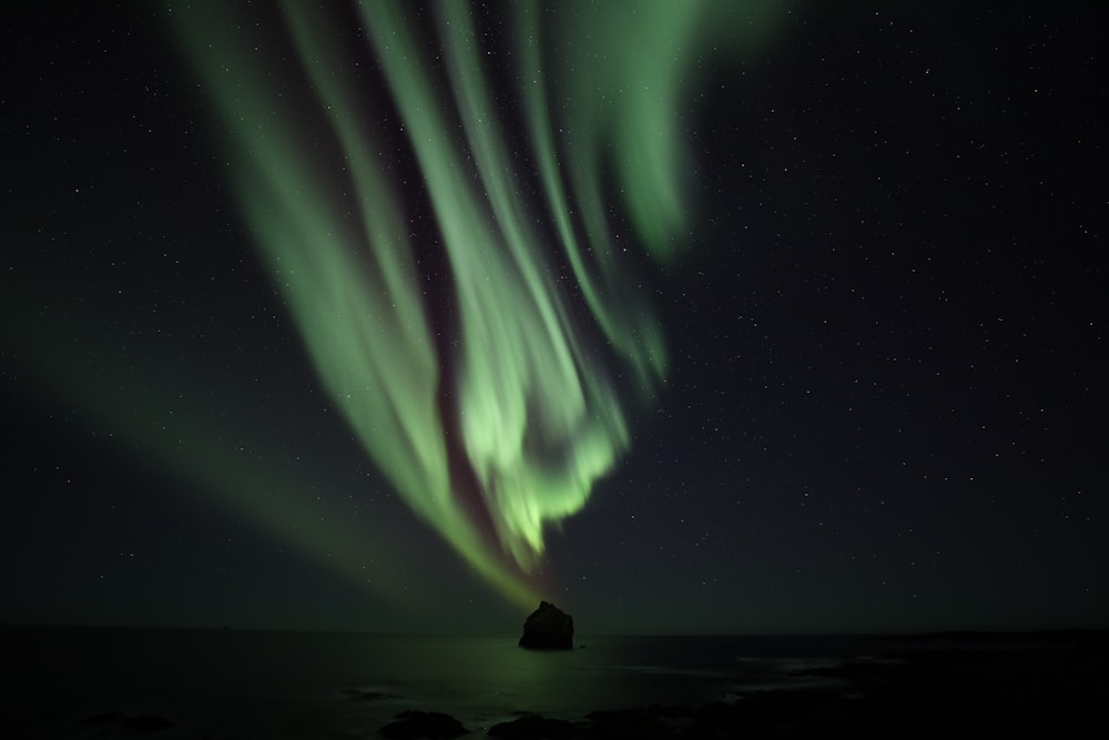 a green and white aurora bore in the night sky