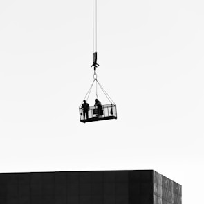 a couple of people hanging from a crane