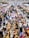 A crowded indoor market or convention center with numerous stalls selling a variety of items. People walk through the aisles, browsing merchandise and engaging with vendors. Colorful displays and products are visible, contributing to a lively atmosphere.
