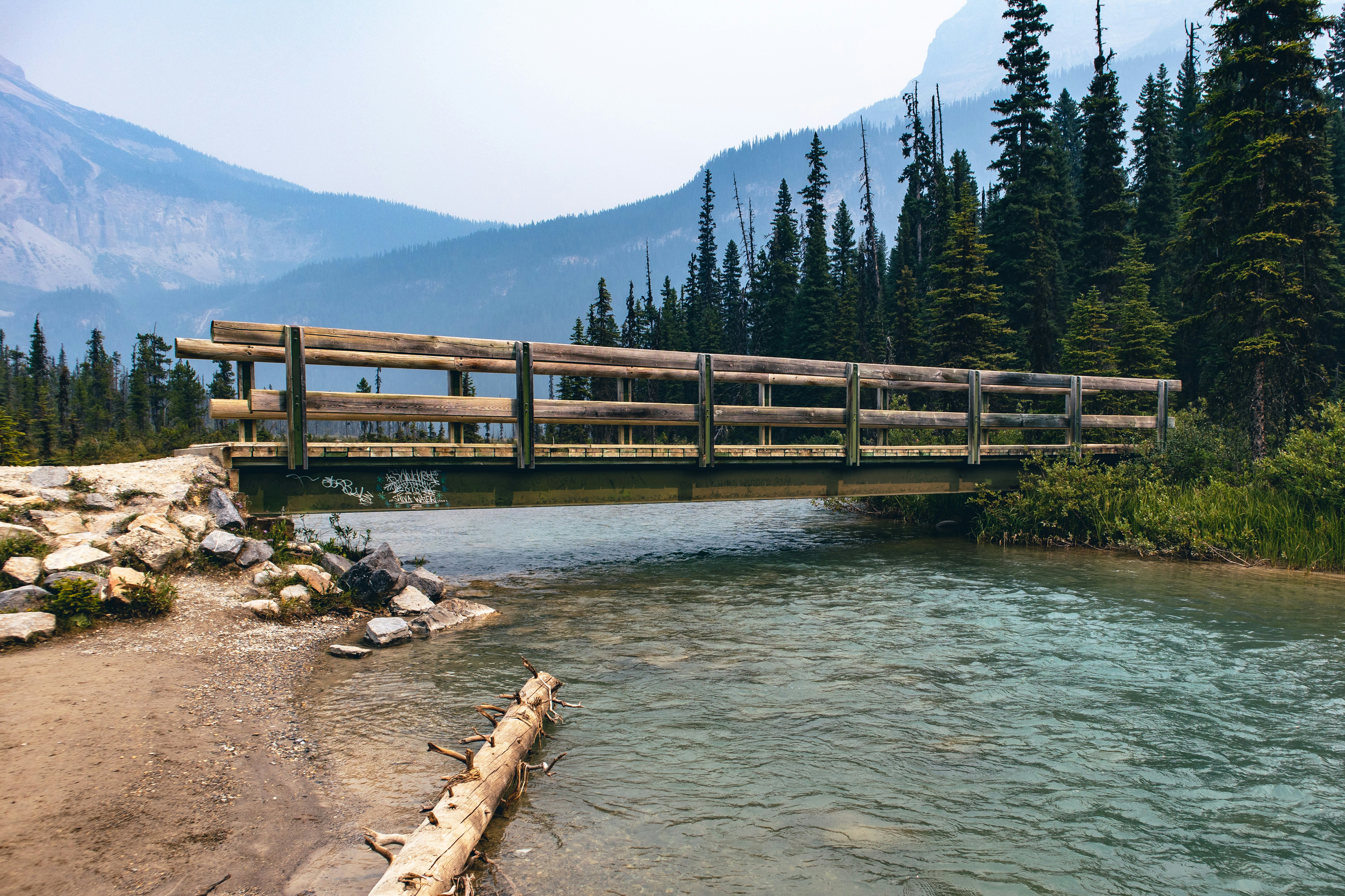 A wooden bridge over a river surrounded by trees photo – Free Lake ...