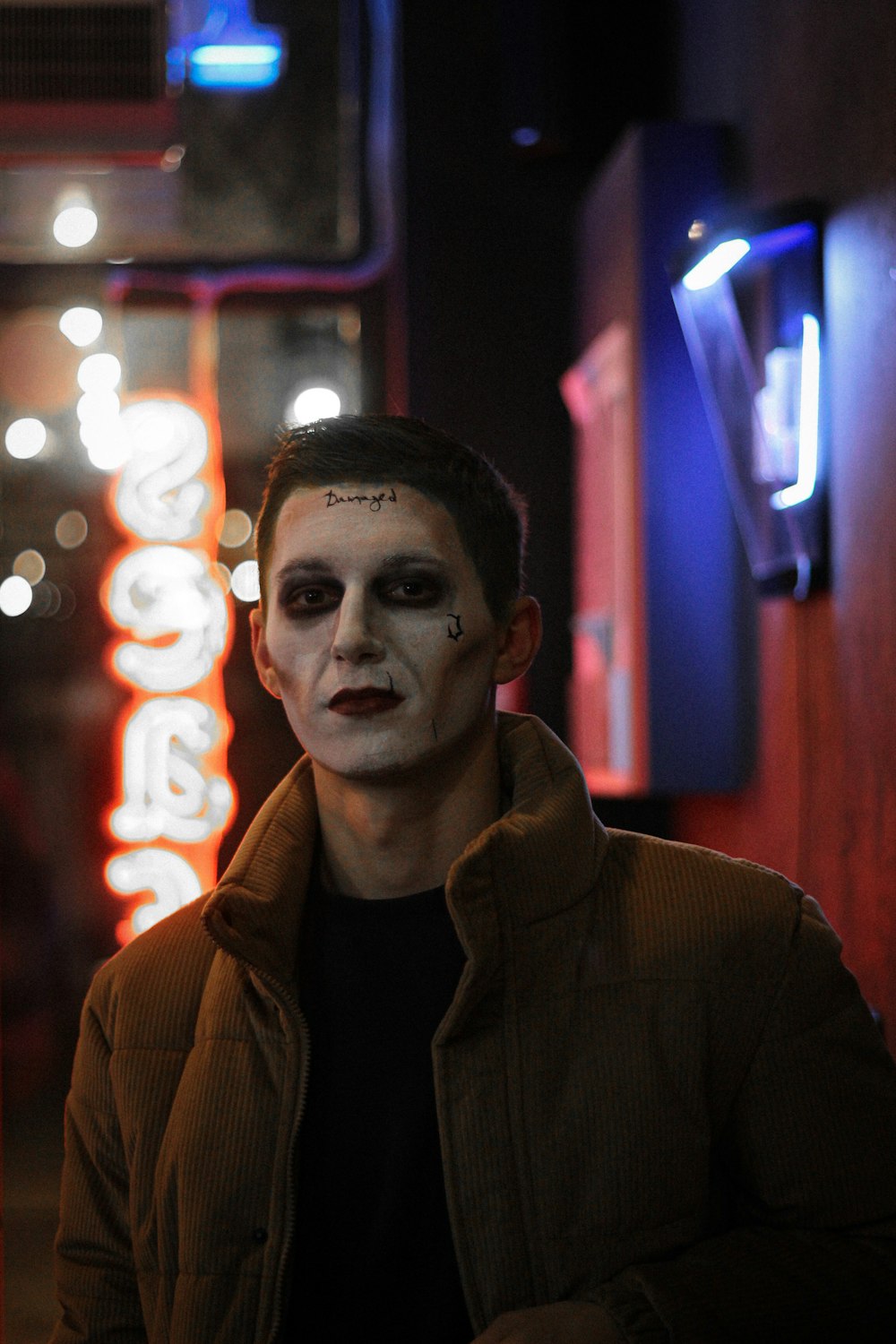 a man in a creepy costume standing in front of a neon sign