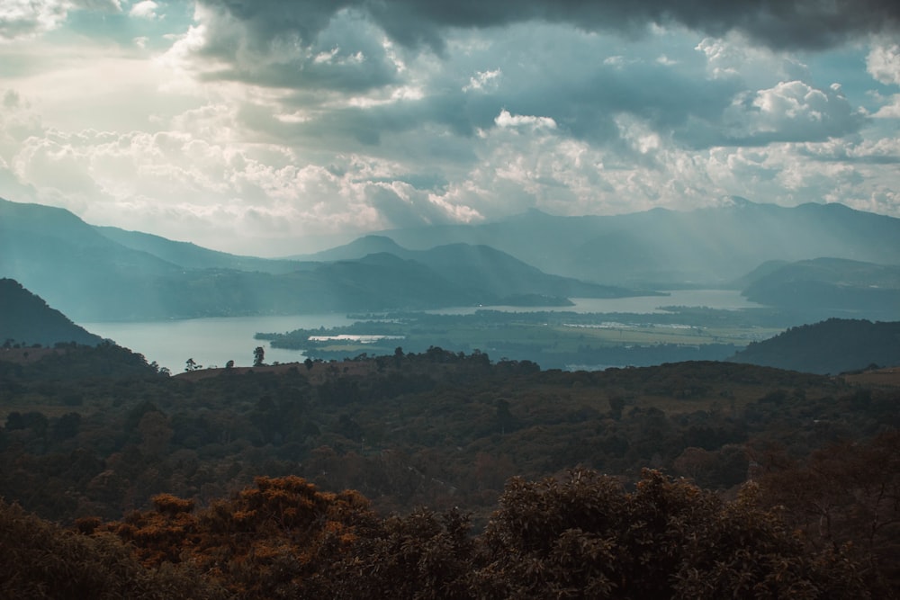 a scenic view of a lake and mountains under a cloudy sky