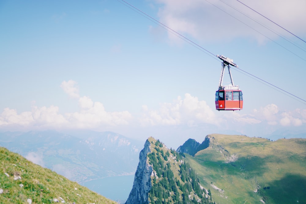 a red cable car going up a mountain side
