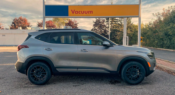 A friendly technician vacuuming the interior of a car parked outside a home.