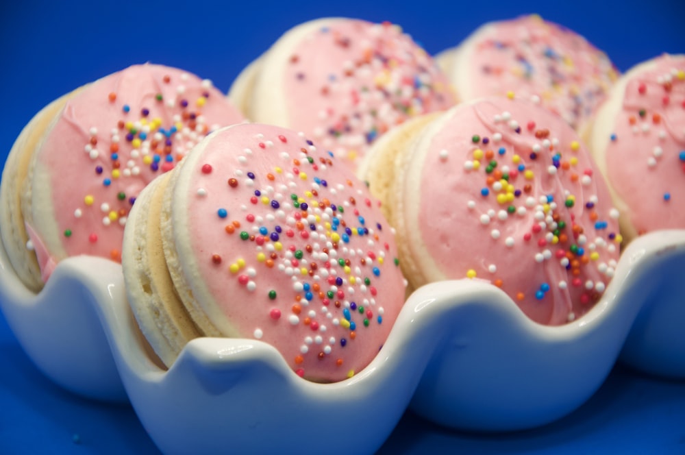 a blue plate topped with pink frosted donuts covered in sprinkles