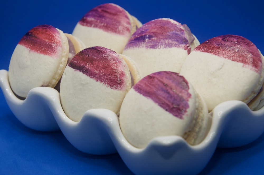 a white bowl filled with purple and white cookies