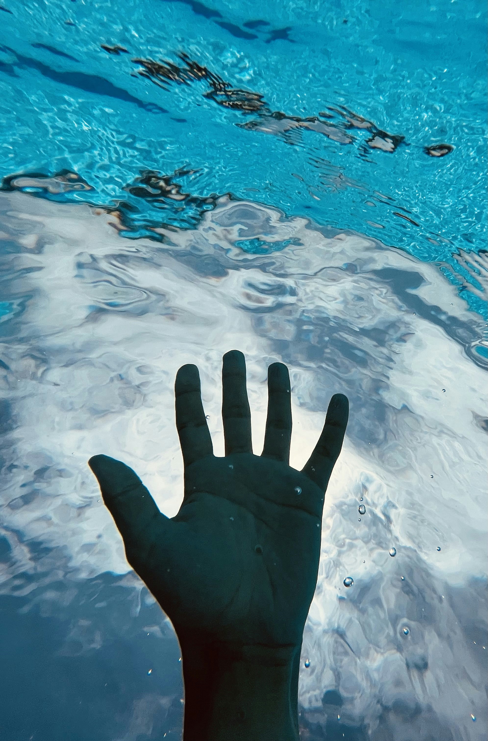 a hand reaching up into a pool of water