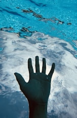 a hand reaching up into a pool of water