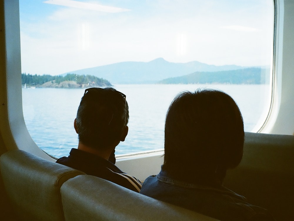 two people looking out a window at a body of water