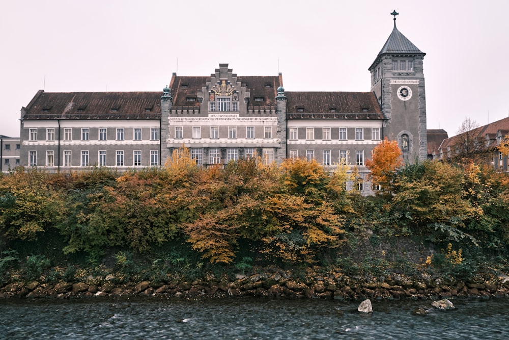 ein großes Gebäude mit einem Uhrturm neben einem Gewässer