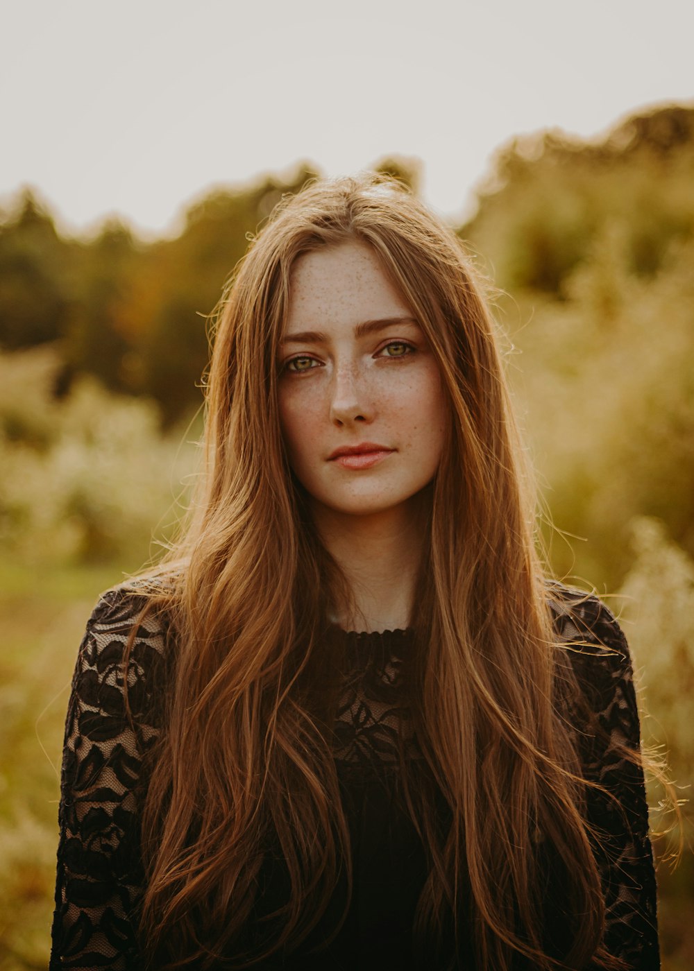 a woman with long hair standing in a field