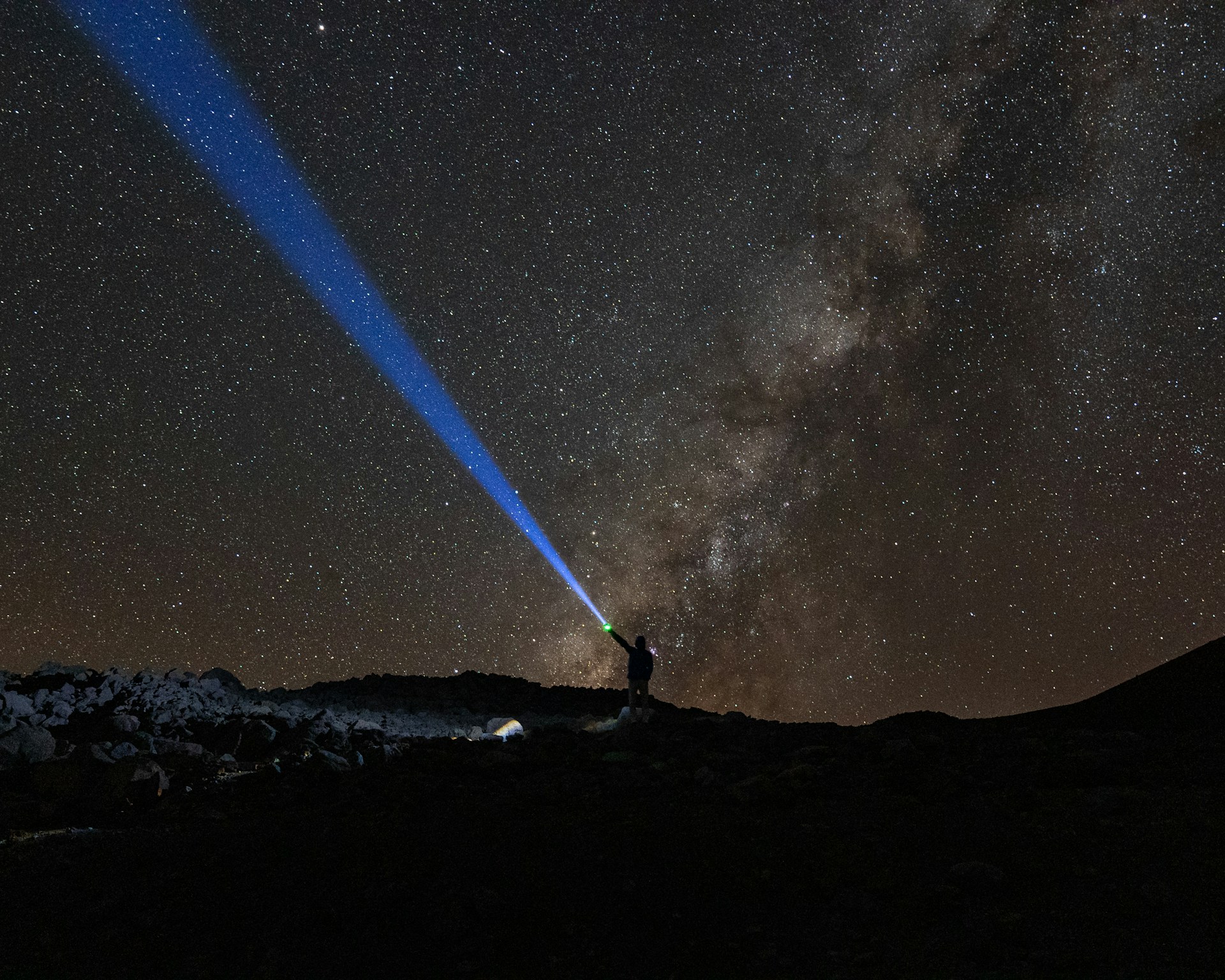 a man standing on top of a mountain under a sky filled with stars