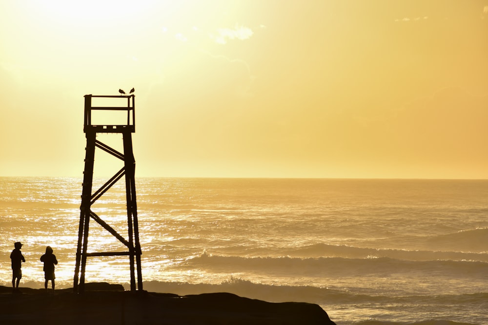 a couple of people standing on top of a beach next to the ocean