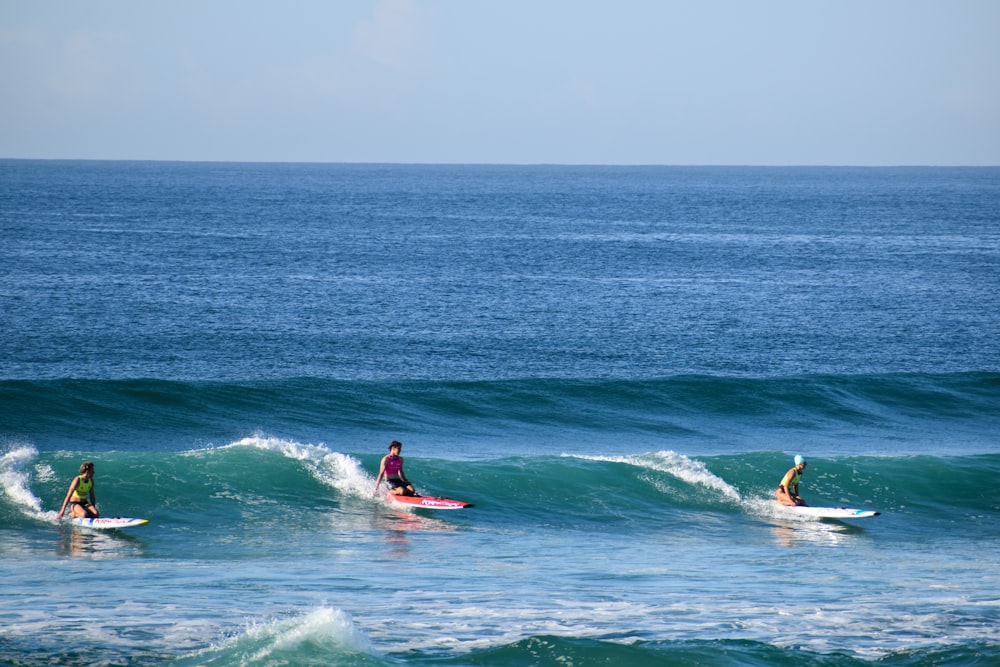 a group of people riding surfboards on top of a wave