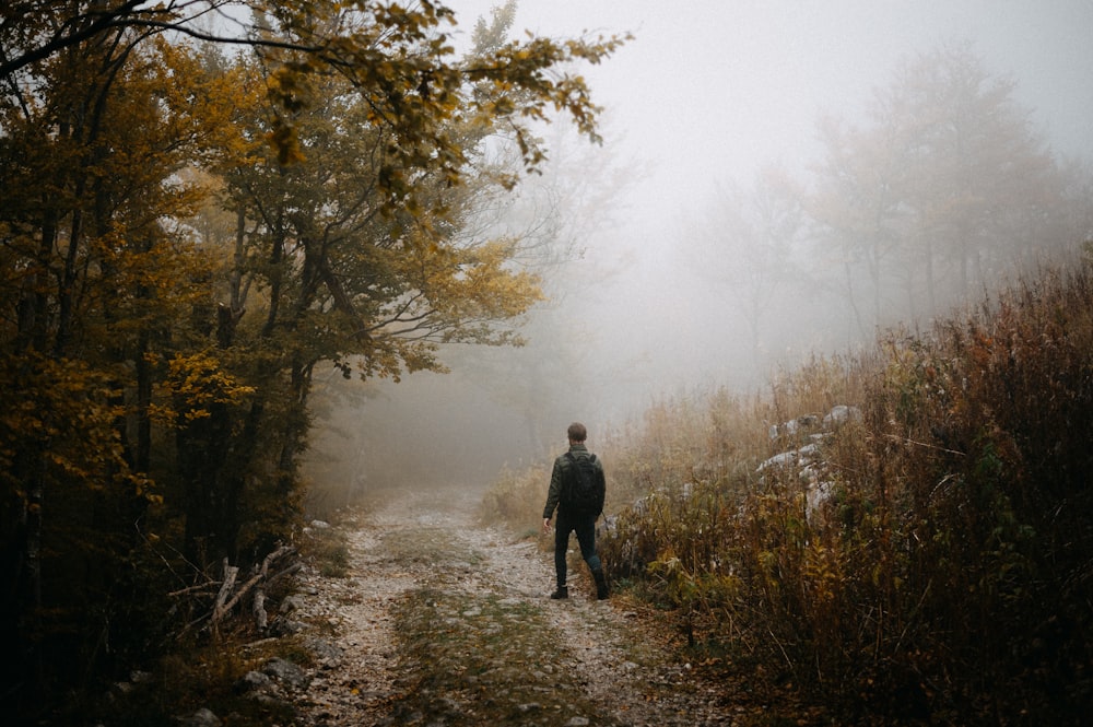 a man walking down a trail in the woods