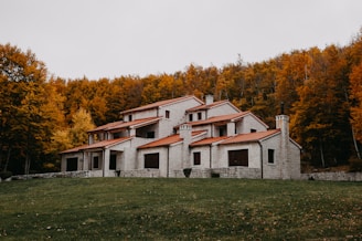 a house in the middle of a field with trees in the background