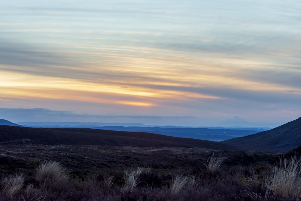 the sun is setting over the mountains in the distance