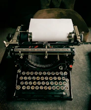 Vintage typewriter with a sheet of paper halfway inserted, ready to type.