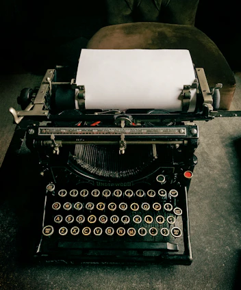 A vintage typewriter with a sheet of paper emerging, set against aged newspaper texture background.