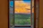 Sunset view from the living room window showing peaceful farmland and distant woods.