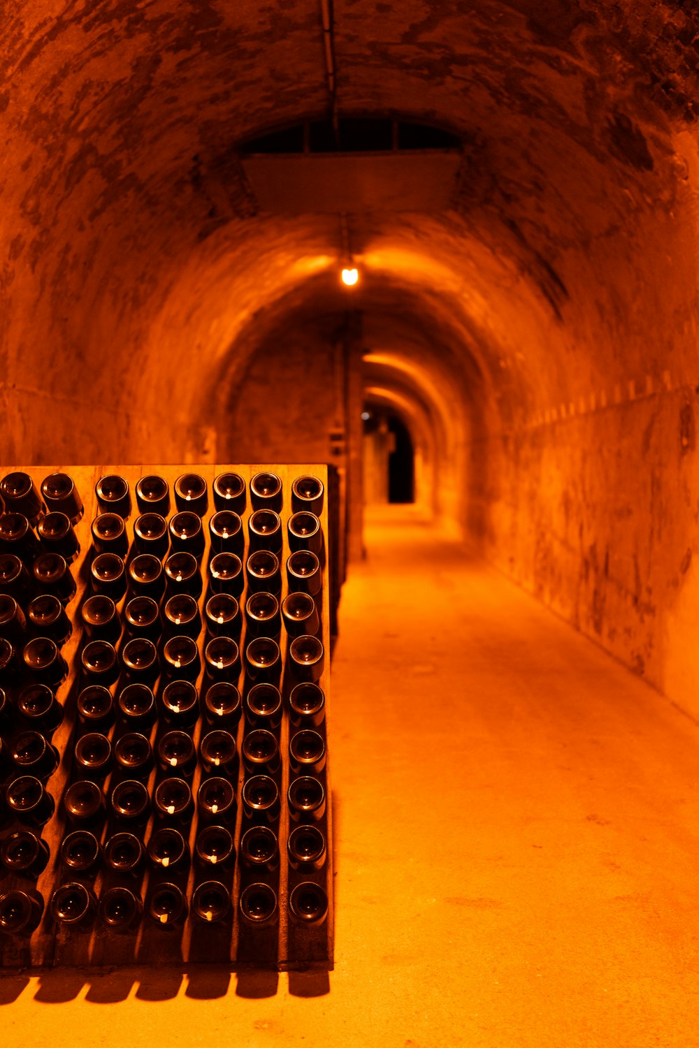 a bunch of wine bottles are lined up in a tunnel