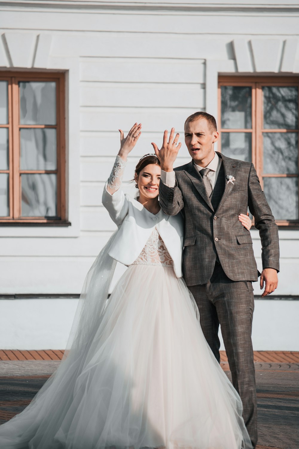 a bride and groom posing for a photo in front of a white building