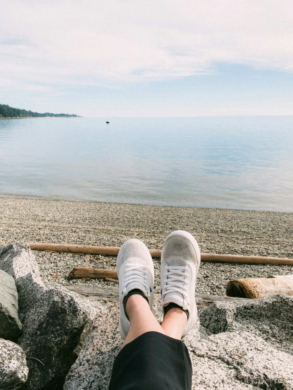 a person sitting on a rock near the water