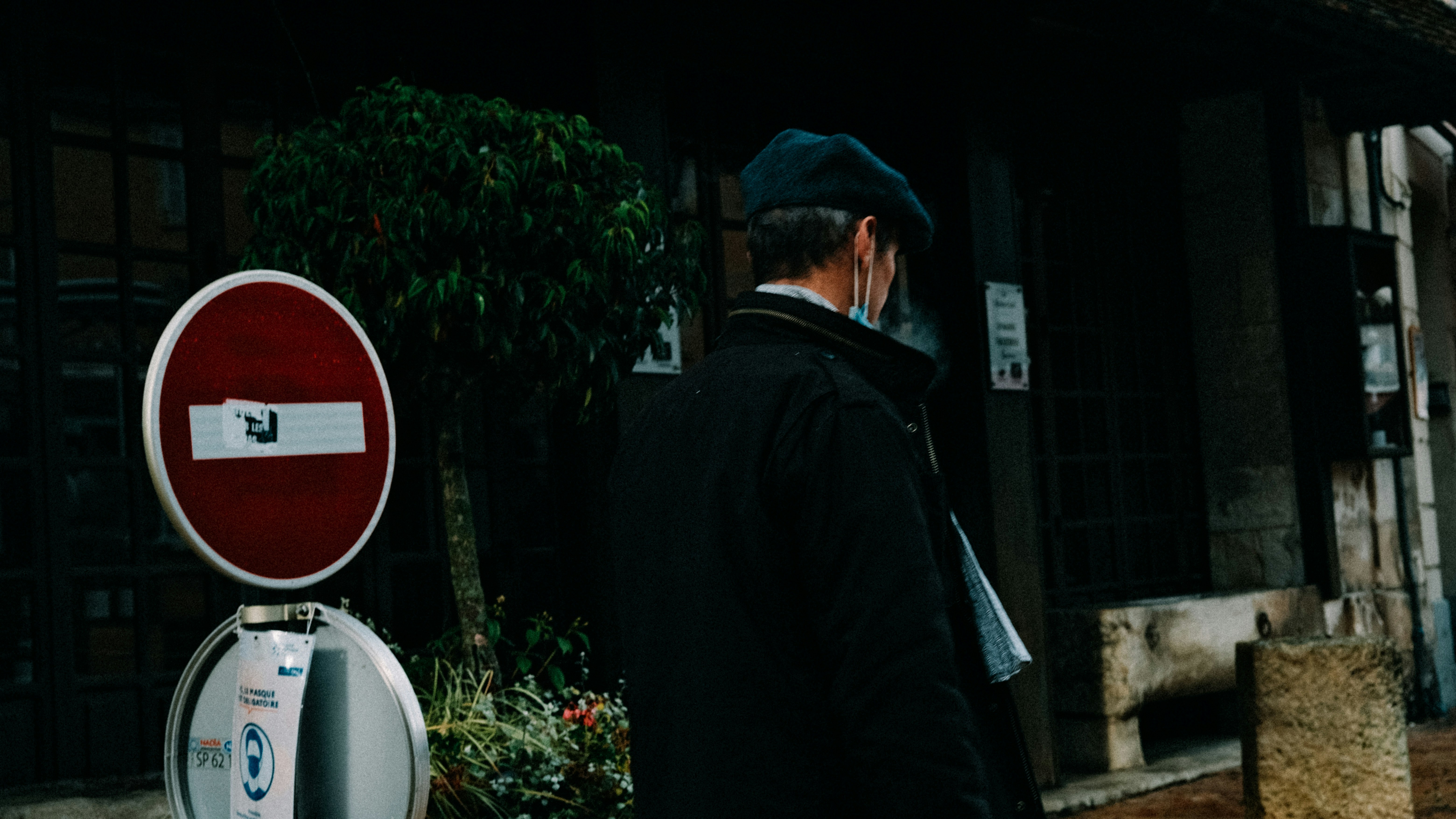 a man standing next to a red and white street sign