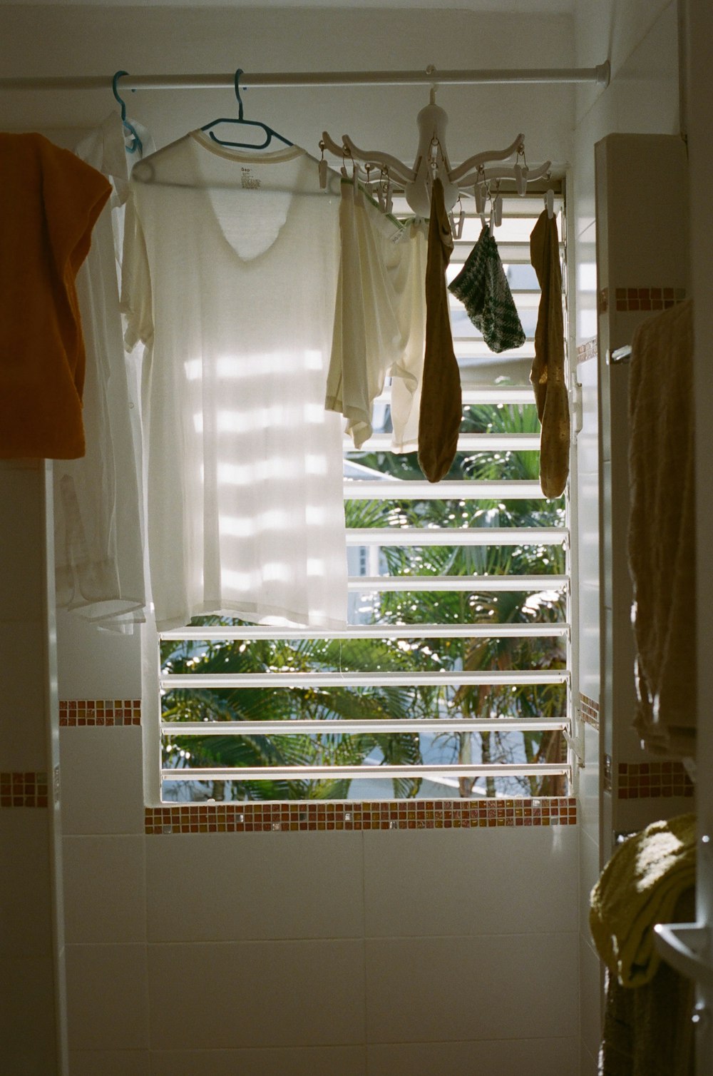 a bathroom with a window and clothes hanging on a rack