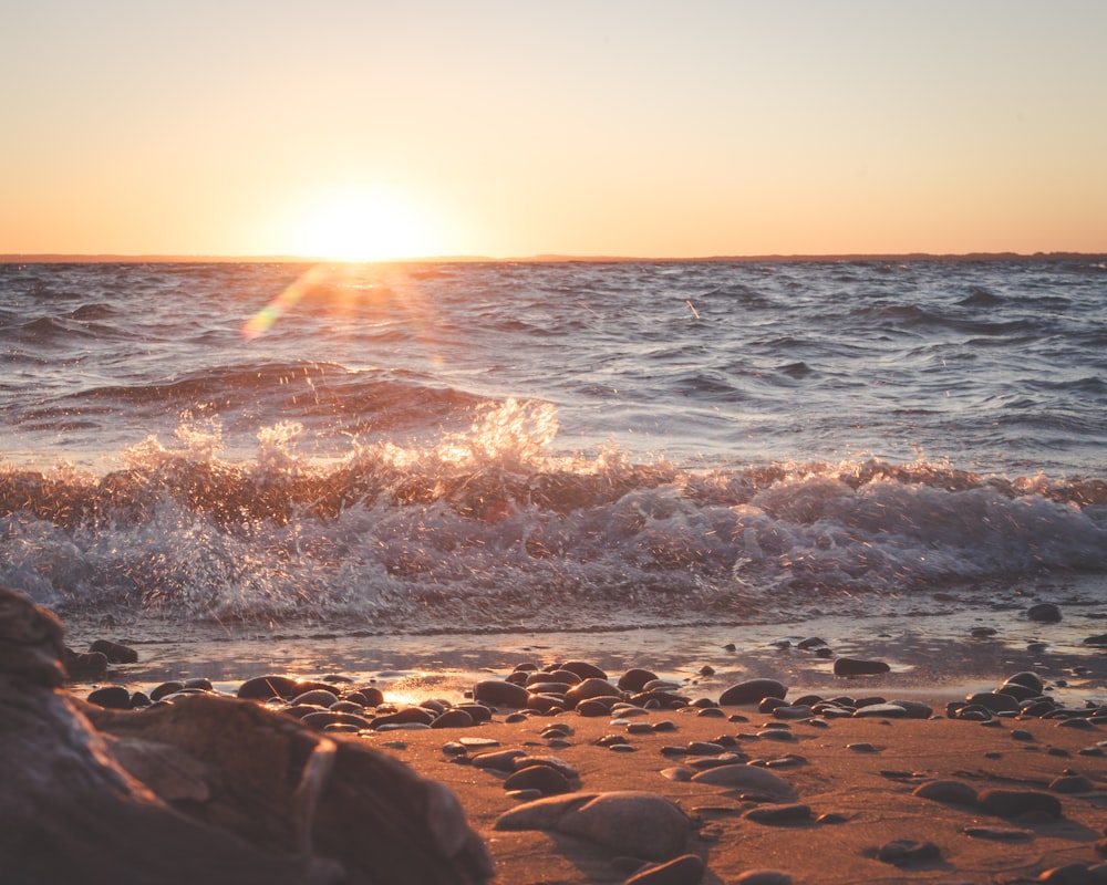 the sun is setting over the ocean waves