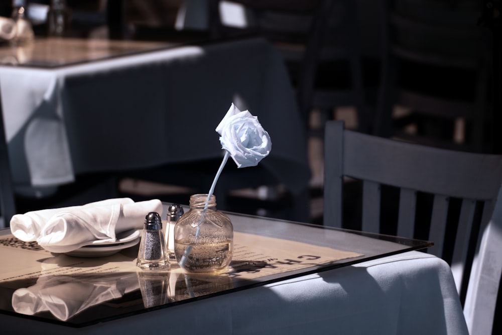 a table topped with a glass vase filled with a flower