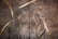 This artwork features two stylized figures in profile, possibly depicting a spiritual or religious scene. The figures are surrounded by halos and are carved into a textured metallic surface, with golden accents emphasizing their forms.