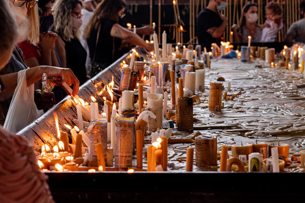 a group of people standing around a long table covered in candles