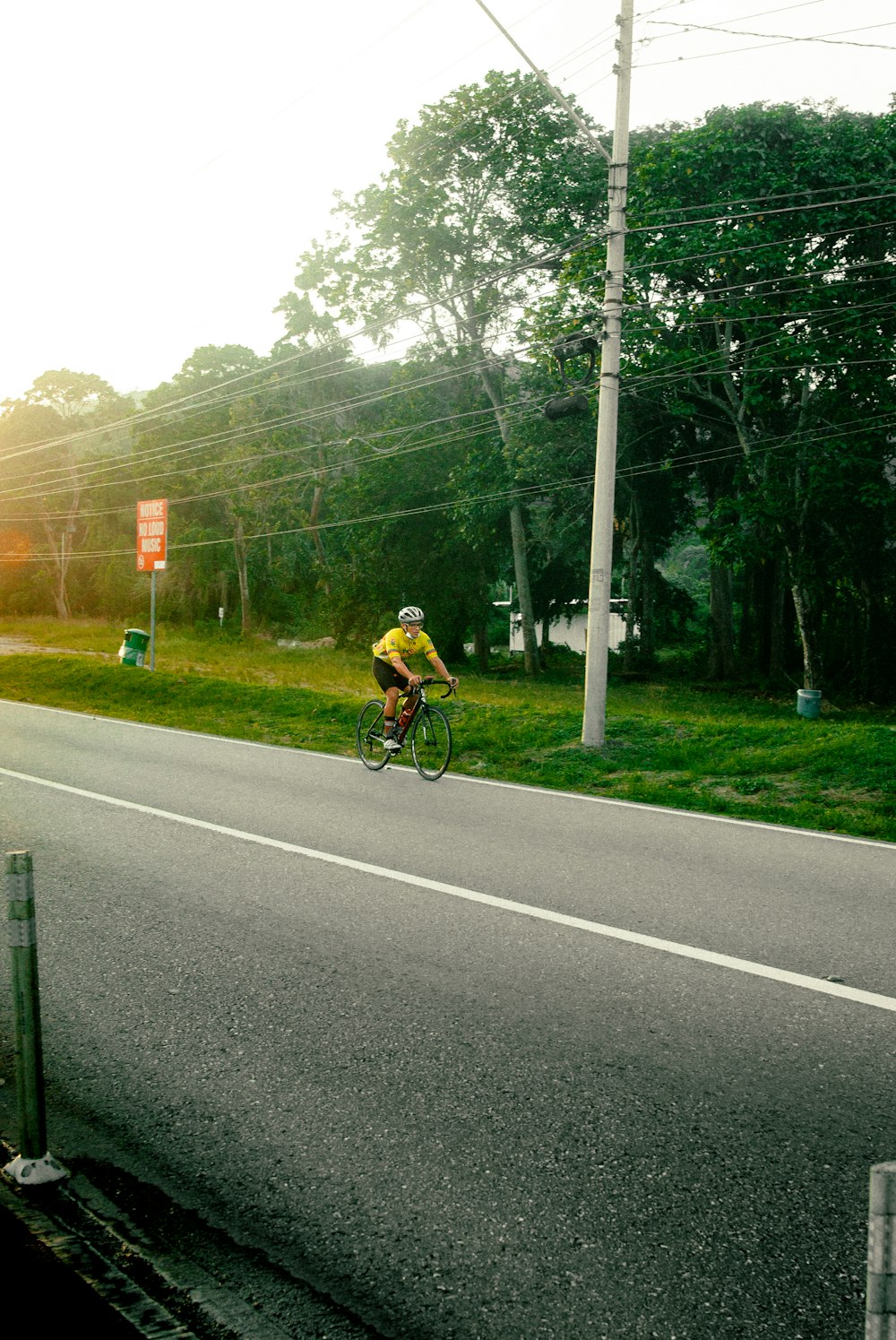 a man riding a bike down a street next to a lush green field