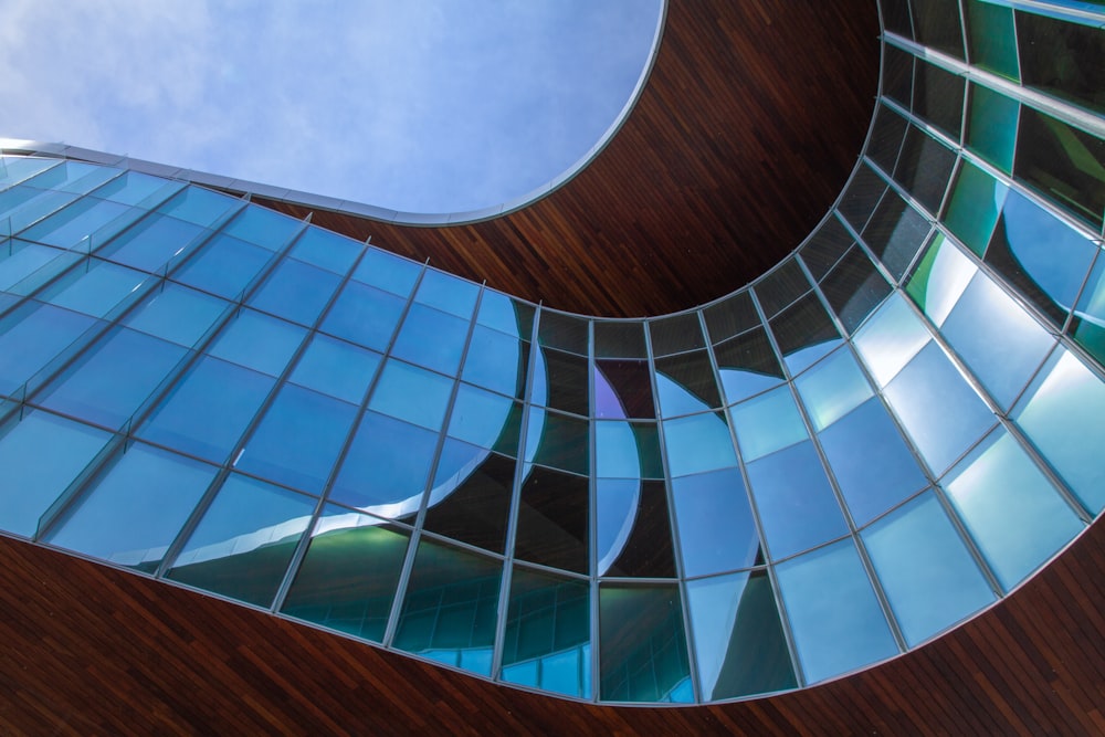 a curved glass building with a sky in the background