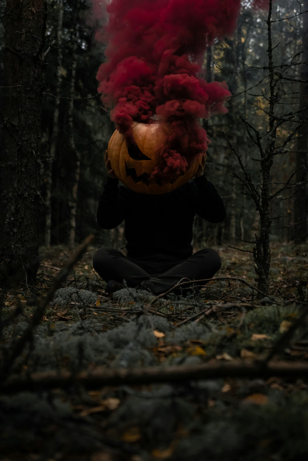 uma pessoa sentada em uma floresta com uma chaminé vermelha na cabeça