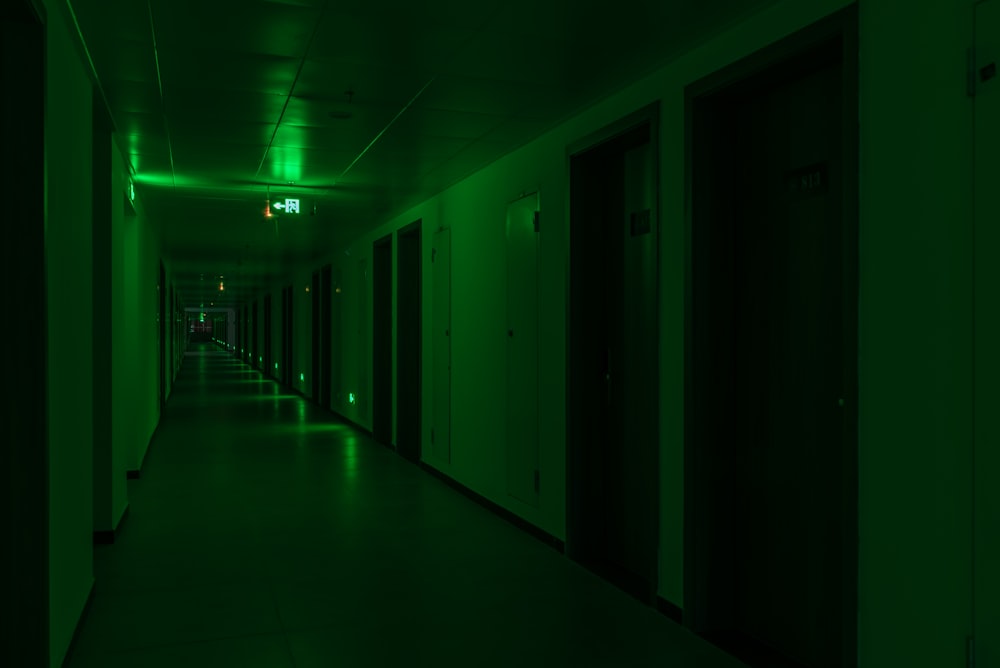 a long dark hallway with green lights on the ceiling
