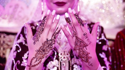 Soft-lit henna ceremony with close-up of intricate henna designs on hands.