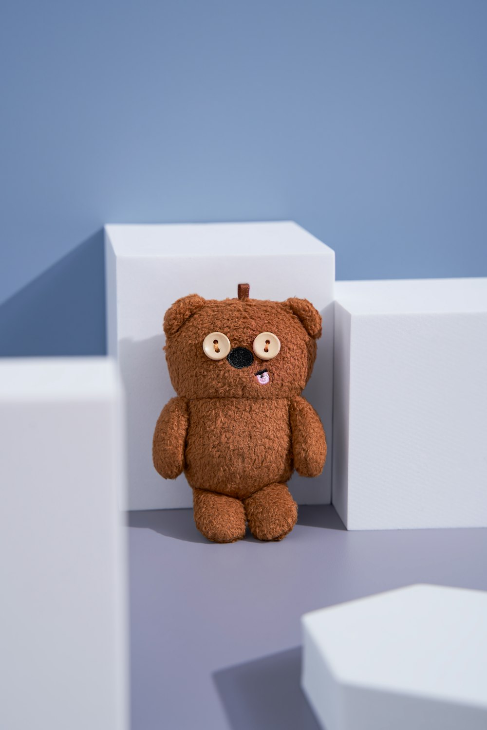 a brown teddy bear sitting on top of a white block