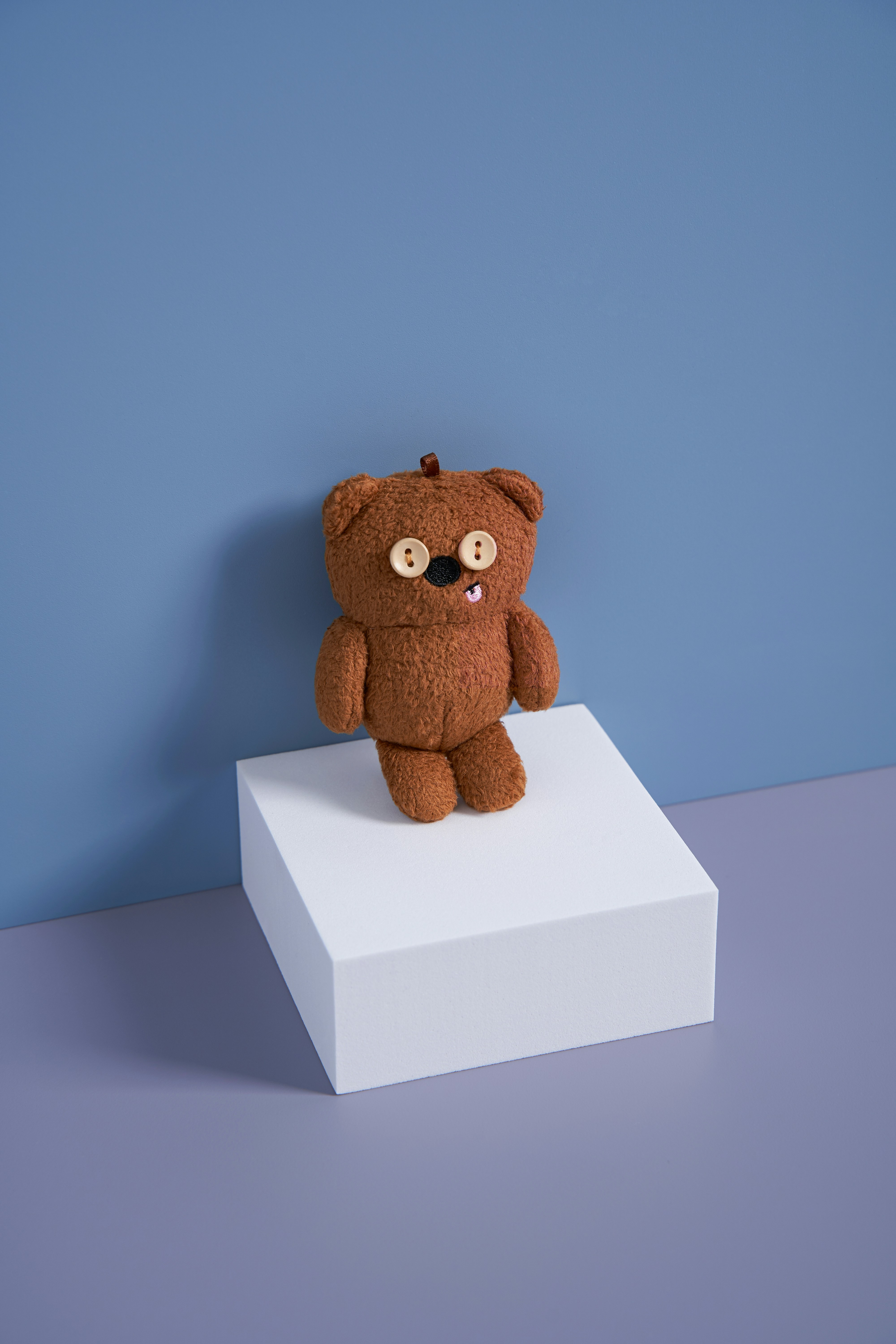 a brown teddy bear sitting on top of a white box