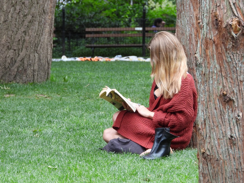 a woman sitting in the grass reading a book