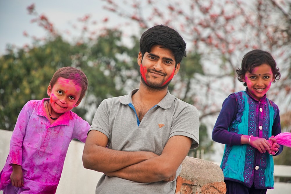 a man standing next to two children covered in paint